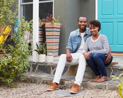 Home owners sitting in front of their house