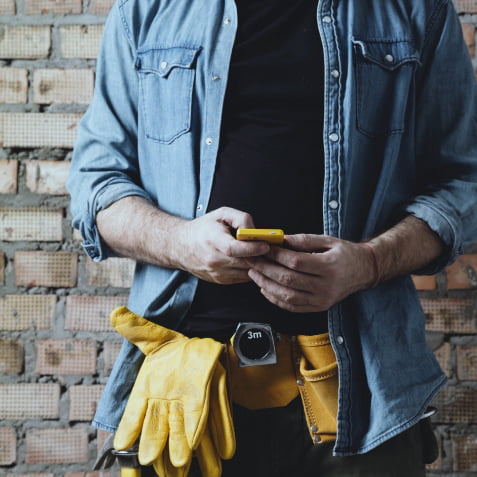 A contractor typing on his phone